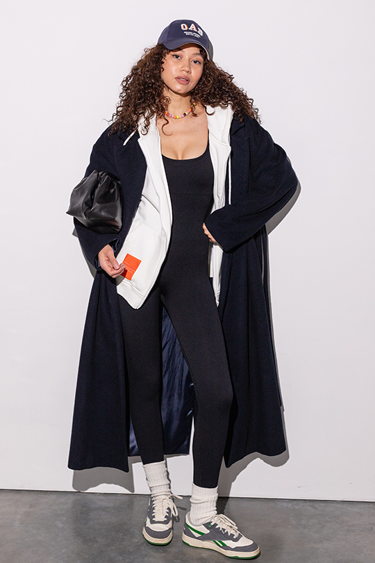 Образ для девушки с черным спортивным комбинезоном YOS DESIGN, белой толстовке Yos и длинном черном пальто. 